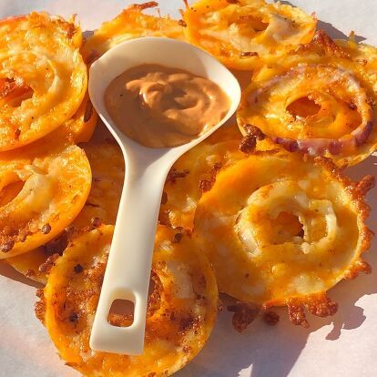 some onion rings with dipping sauce on top