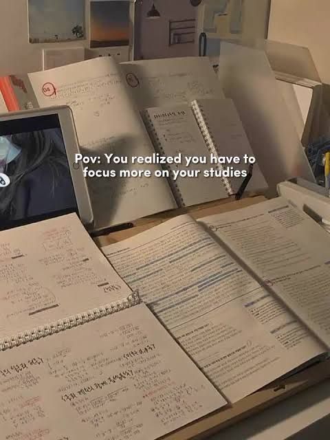 an open laptop computer sitting on top of a desk covered in books and notebooks