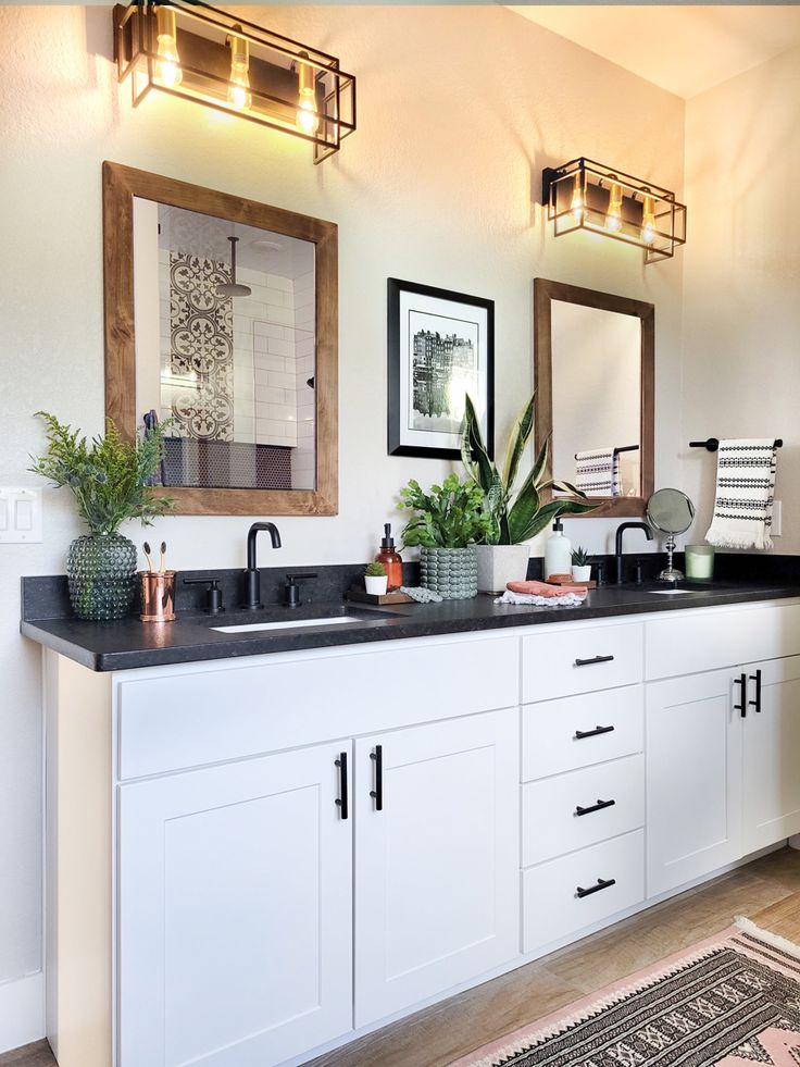 a bathroom with two sinks, mirrors and plants on the counter top in front of it