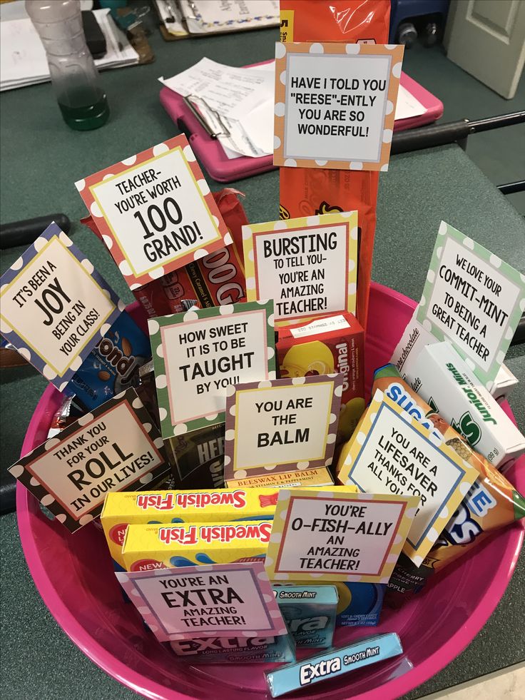 a pink bowl filled with lots of different types of candies and cards on top of each other