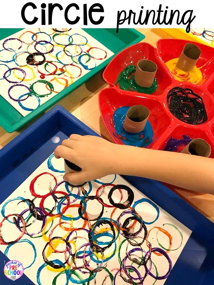 a child's hand painting circles on a tray with crayons and glue