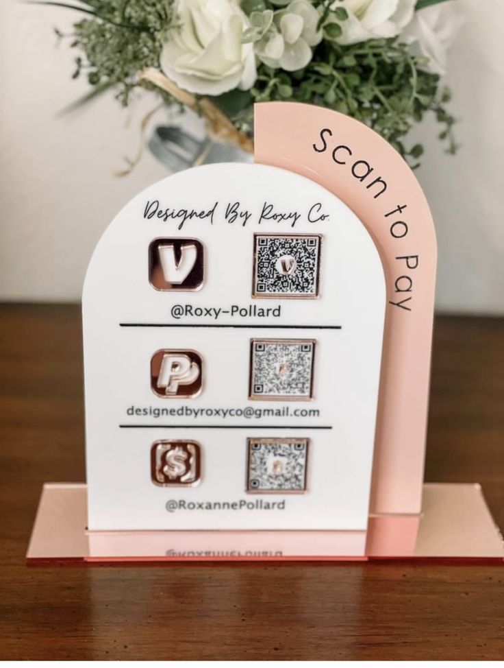 a pink and white card with four different types of stamps on it, sitting next to a bouquet of flowers