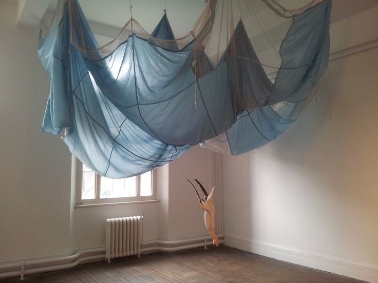 a room that has some kind of blue net hanging from it's ceiling in front of a window