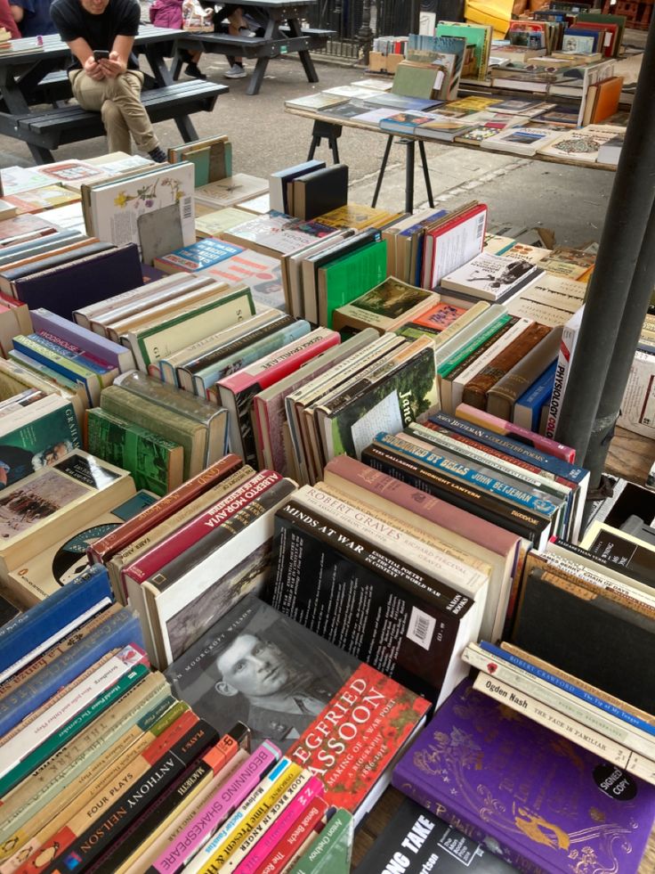 a man sitting on a bench next to a pile of books