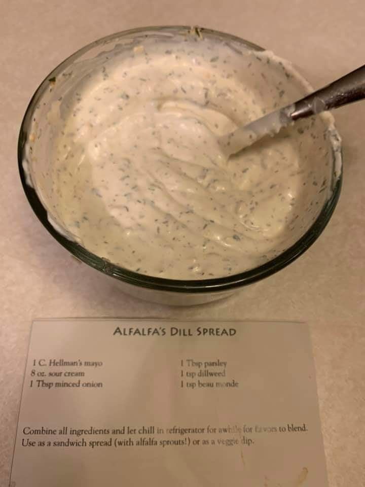 a glass bowl filled with white sauce sitting on top of a table next to a paper