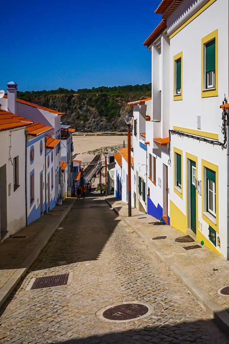 an empty street with white and yellow buildings