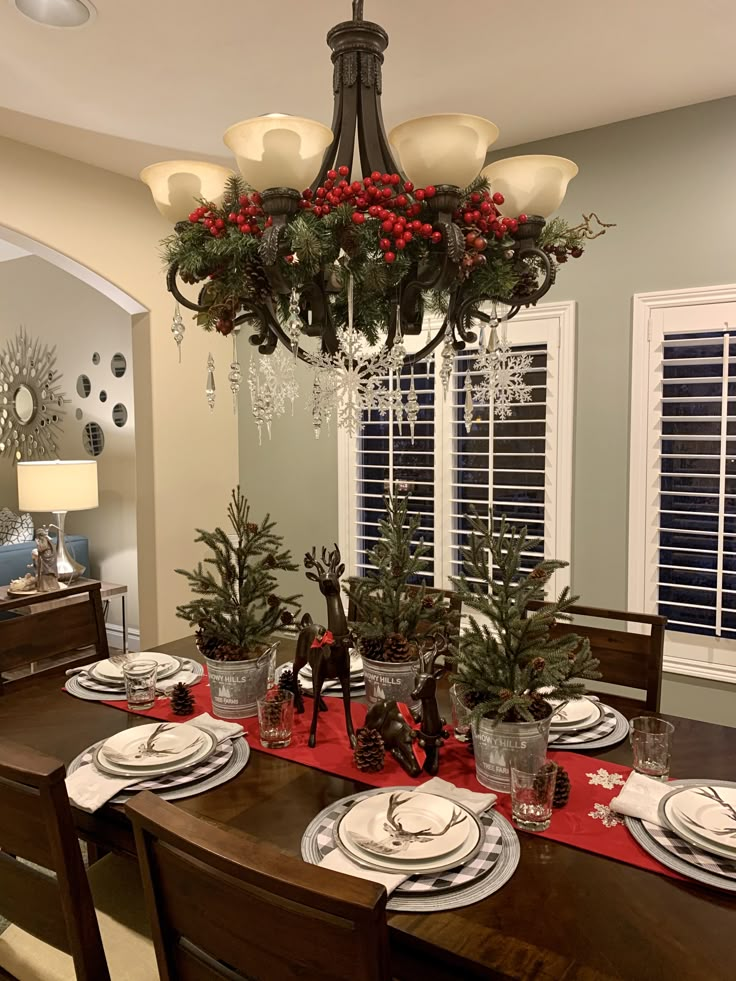 a dining room table set for christmas with place settings and decorations on the table top