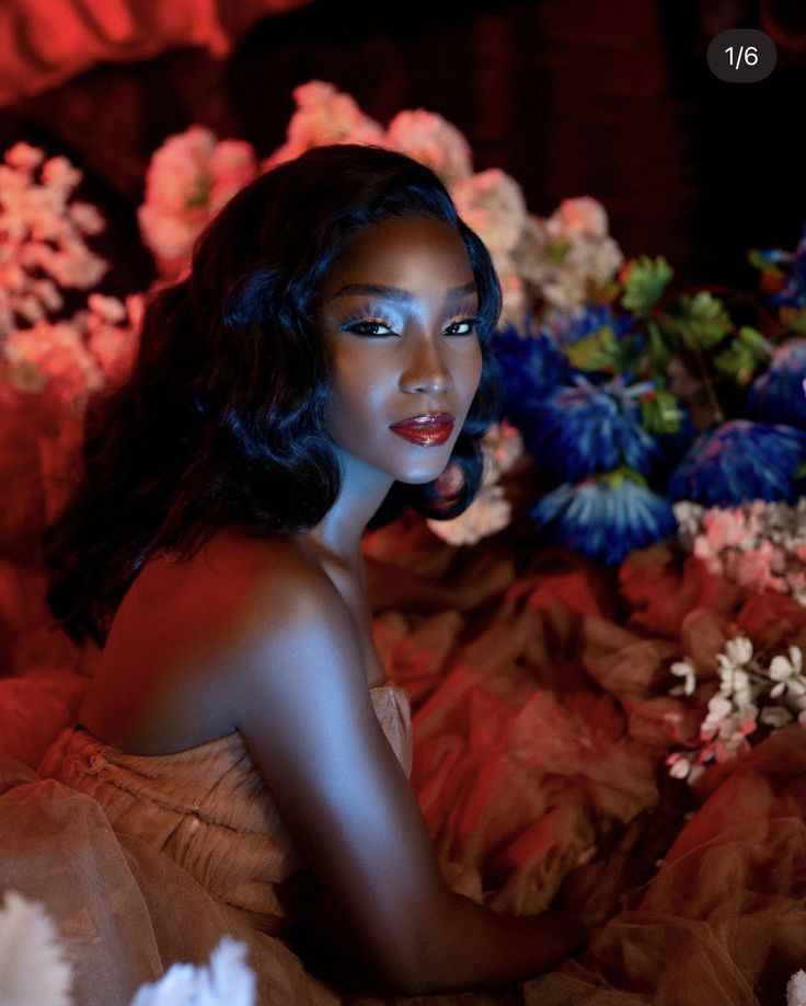 a woman is sitting on a bed with flowers in the background