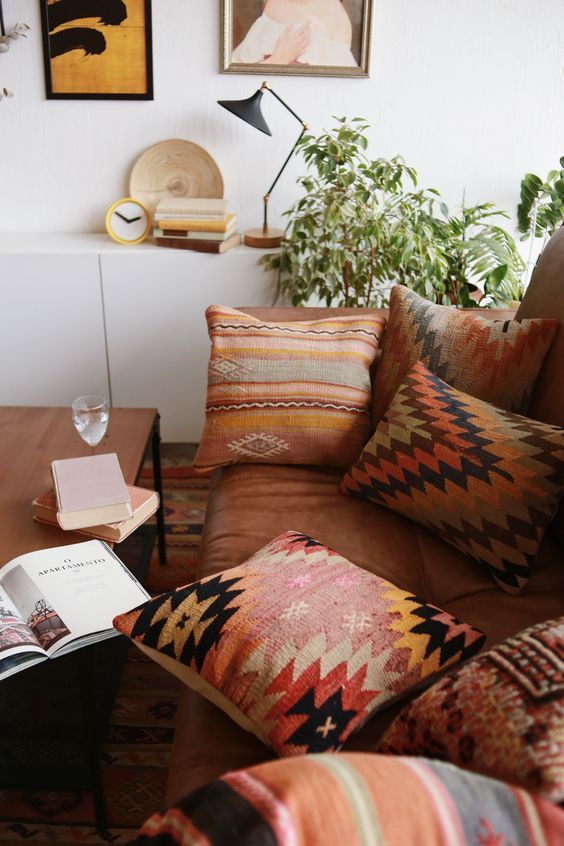 a living room filled with lots of furniture and pillows on top of a brown couch