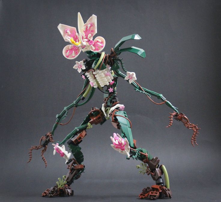 an action figure made out of legos with flowers on the body and arms, in front of a gray background