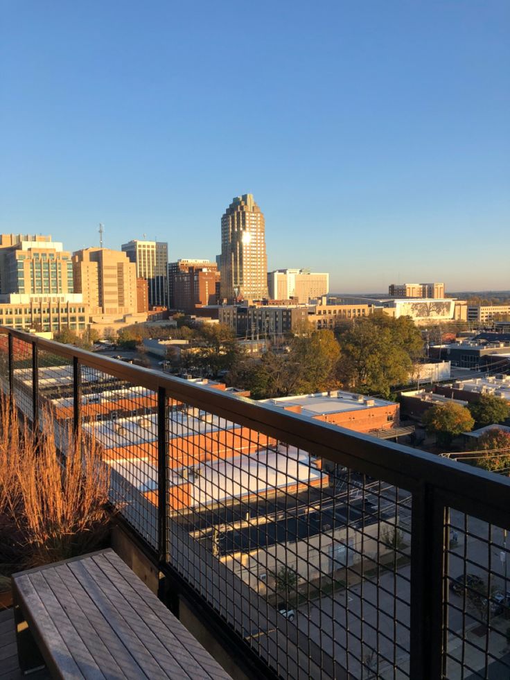 a wooden bench sitting on top of a balcony next to a tall cityscape