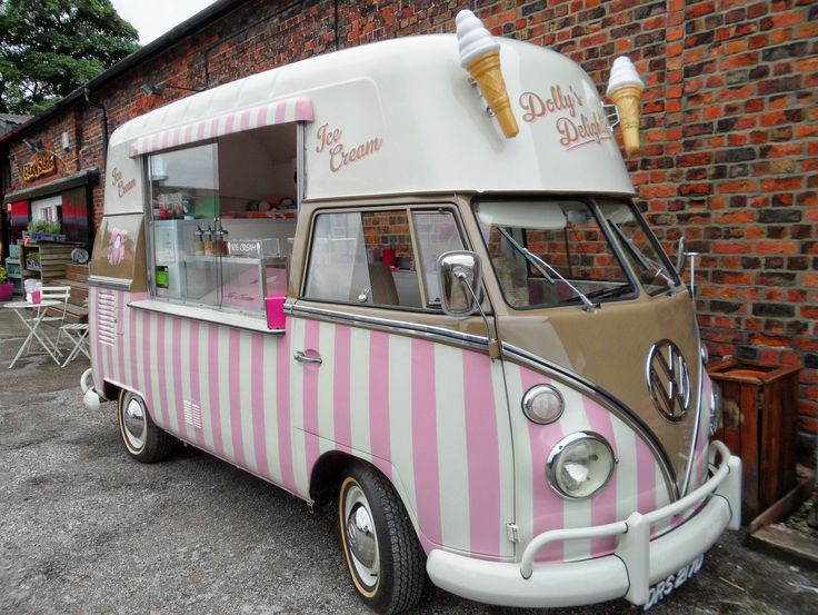 an ice cream truck parked in front of a brick building with tables and chairs around it