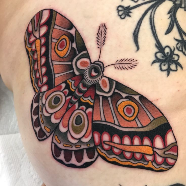 a colorful butterfly tattoo on the back of a woman's stomach