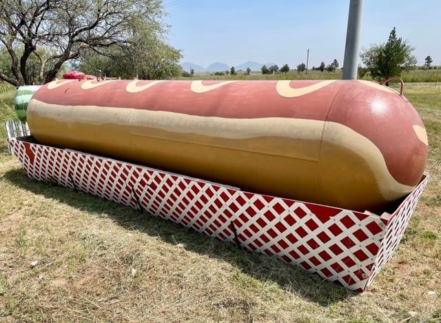 a large hot dog sitting in a basket on the ground