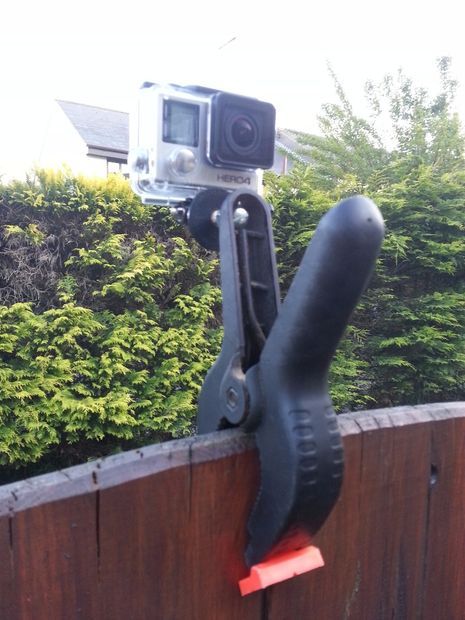 a camera attached to the side of a wooden barrel next to trees and shrubbery