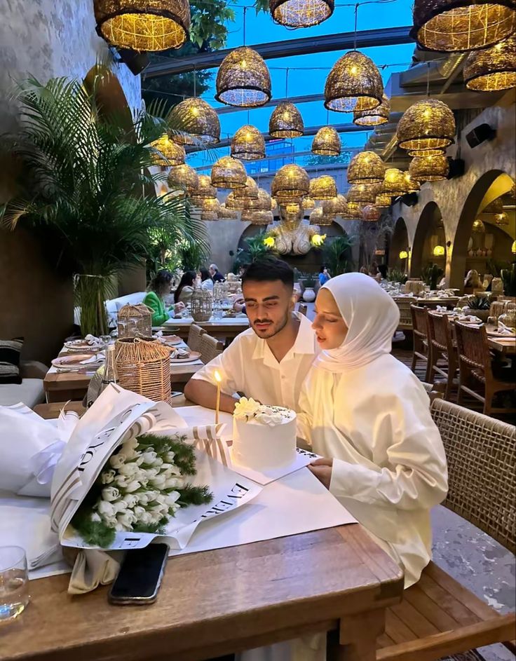 a man and woman sitting at a table in front of a cake