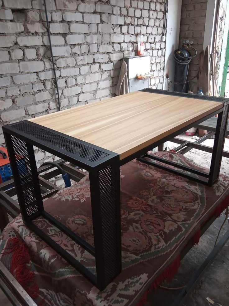 a wooden table sitting on top of a rug next to a brick wall and floor