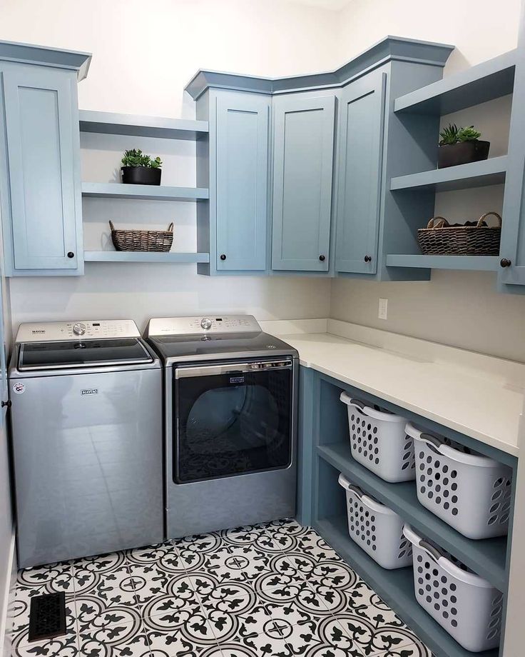 a washer and dryer in a laundry room with blue cabinets, patterned floor tiles