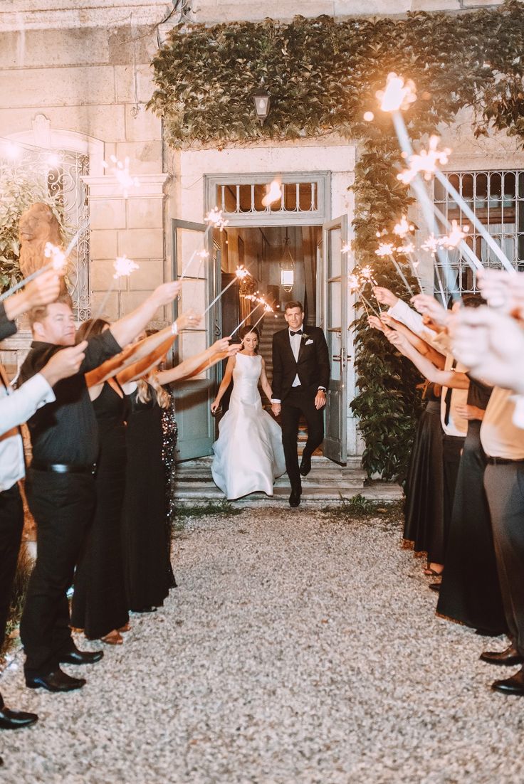 a bride and groom walking down the aisle with sparklers in front of their heads