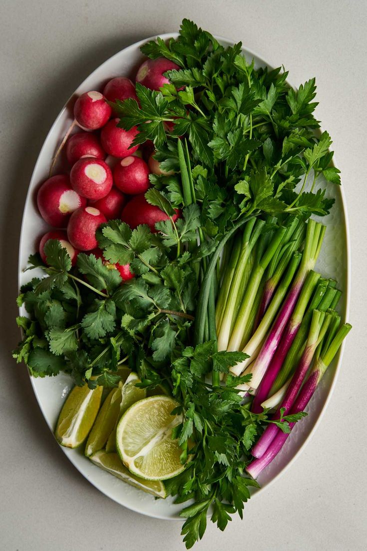 a plate with radishes, celery, and limes on it