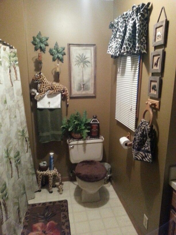 this bathroom has giraffes and other decorations on the wall above the toilet