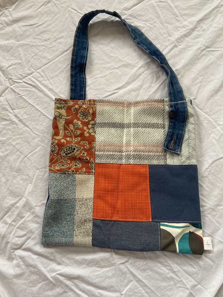 a multicolored patchwork bag sitting on top of a white sheet