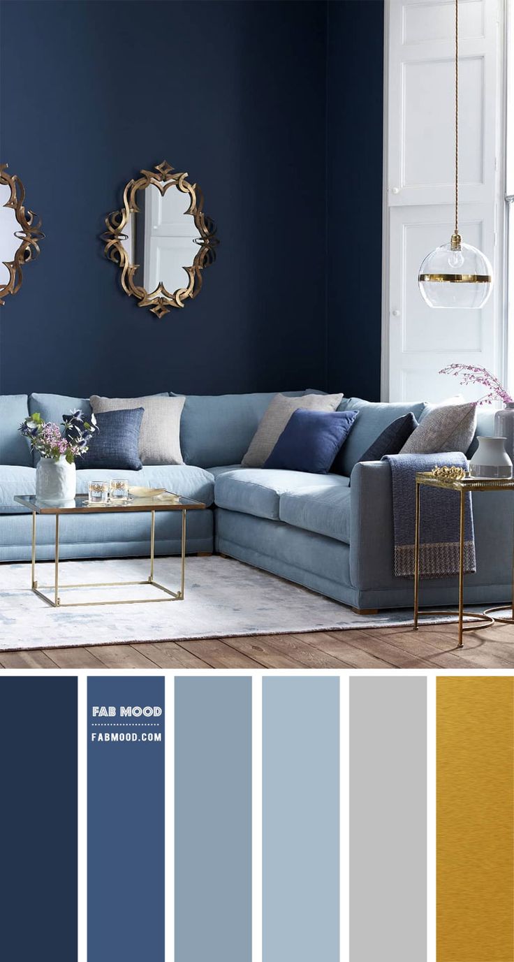 a living room with blue walls and gold accents in the color scheme, along with two mirrors on the wall