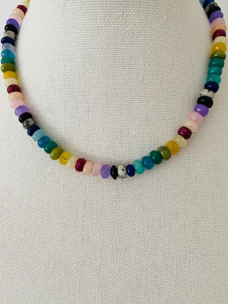 This necklace is a vibrant and eye-catching piece of jewelry that features colorful rondelle beads in a rainbow spectrum of shades. The necklace measures approximately 17 inches in length and can be adjusted to a shorter length, allowing for a customized fit. The rondelle beads are small, cylindrical-shaped beads that have been faceted to catch and reflect light, enhancing their brilliance and adding a touch of sparkle to the necklace. The beads are arranged in a rainbow pattern, with each color Adjustable Rainbow Beaded Necklace, Colorful Adjustable Beaded Necklace With Polished Beads, Colorful Adjustable Beaded Necklaces With Polished Beads, Adjustable Multicolor Crystal Necklace With Large Beads, Adjustable Multicolor Crystal Necklaces With Large Beads, Rainbow Rondelle Necklace For Gift, Rainbow Rondelle Necklace Gift, Colorful Faceted Round Bead Necklaces, Adjustable Rainbow Crystal Necklace With Faceted Beads