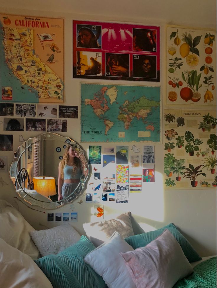 a woman is standing in front of a mirror on a wall covered with pictures and posters