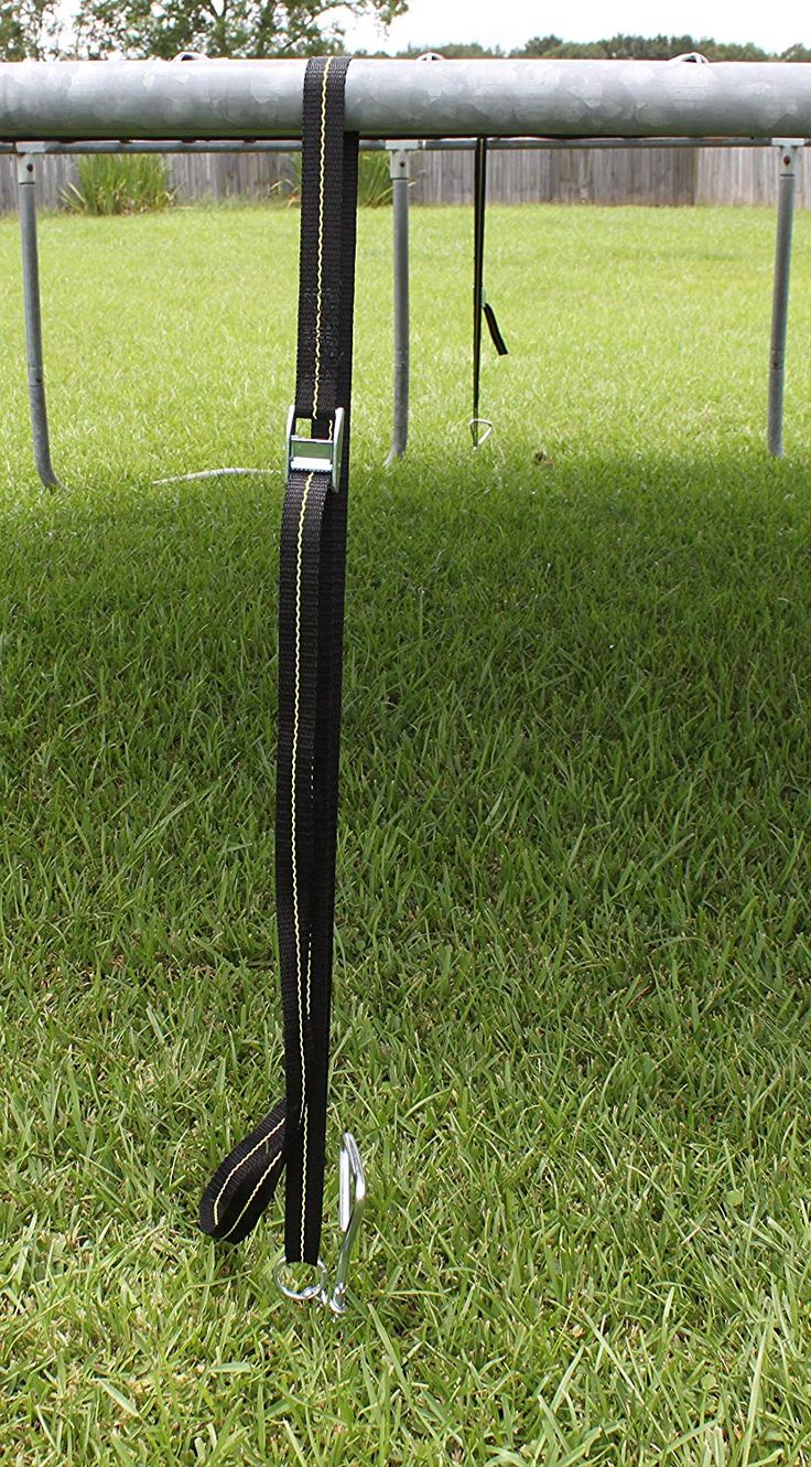 a pair of black luggage bags sitting on top of a grass covered field next to a metal rail