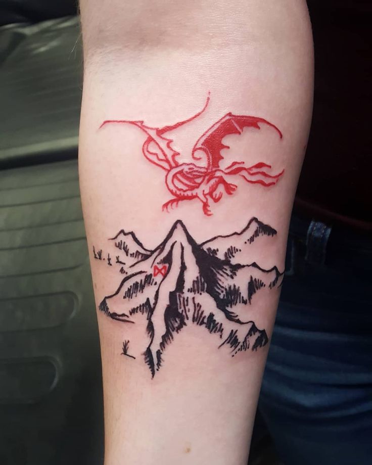 a tattoo on the leg of a person with mountains and a bird flying over it