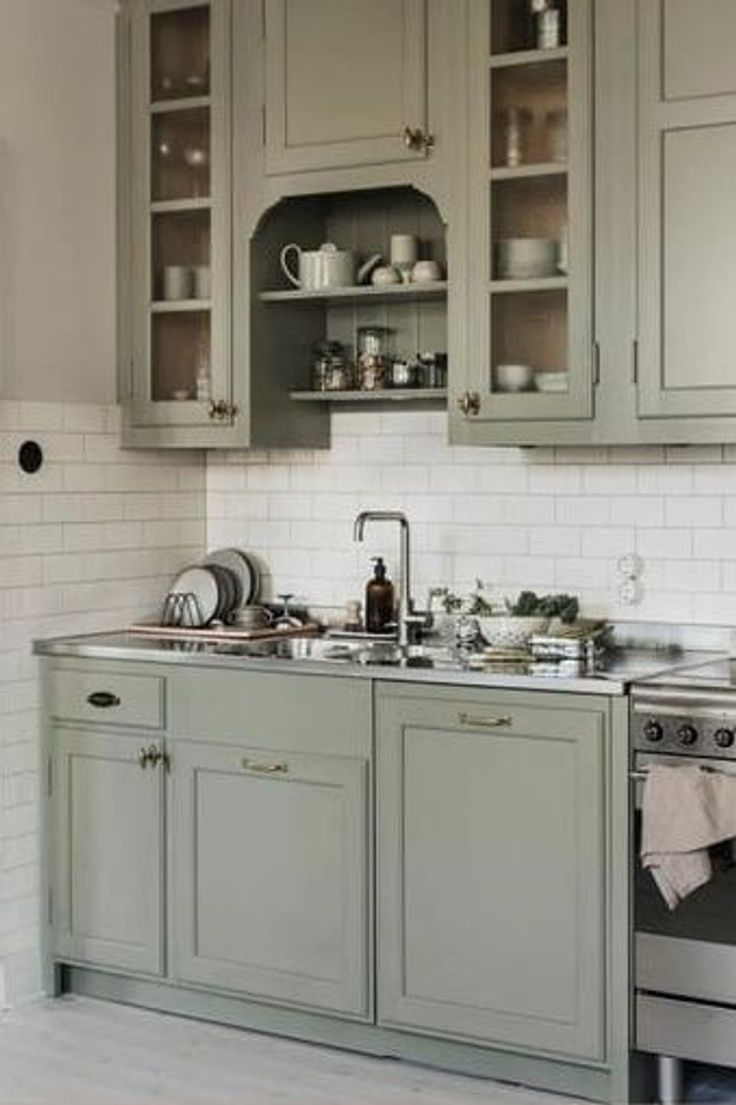 a kitchen with gray cabinets and silver appliances