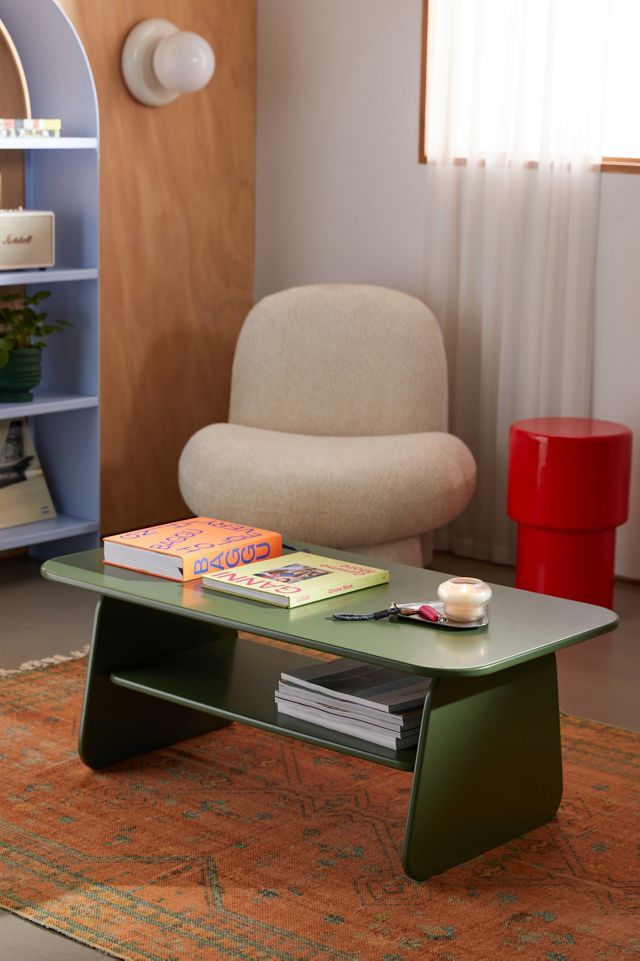 a living room with a chair, coffee table and bookshelf on the floor