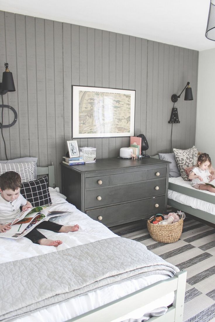 two children are laying on their beds in the same room, one reading a book