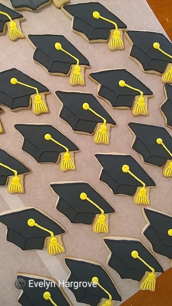 decorated cookies in the shape of graduation caps and tassels are displayed on a table