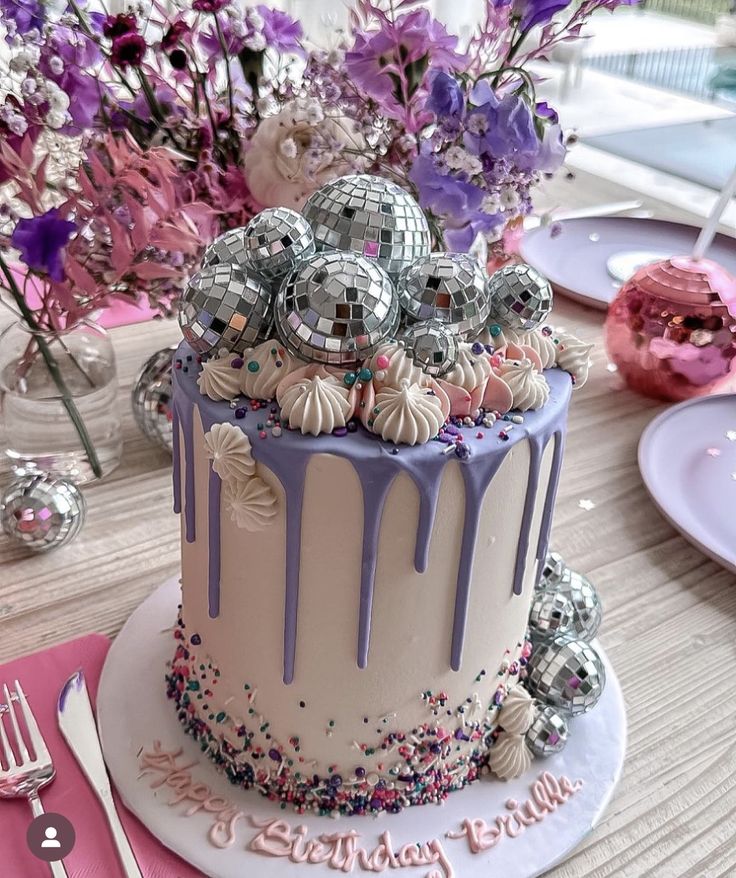 a birthday cake decorated with disco balls and sprinkles on a wooden table