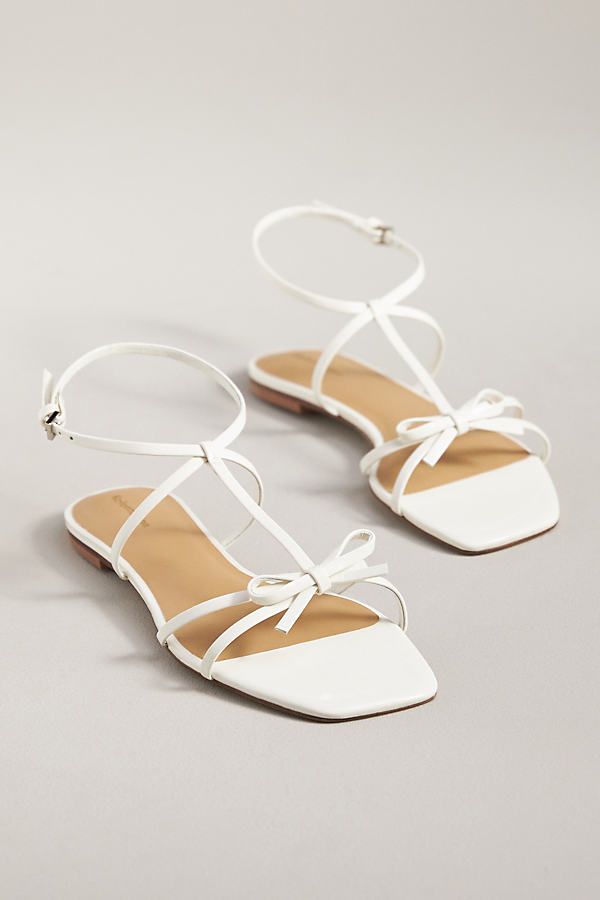 The Reformation Maya Bow Sandals feature a square toe, ankle strap, and delicate bow at the toe for a sweet springtime sandal. | Maya Bow Sandals by Reformation in White, Women's, Size: 6.5, Leather/Rubber at Anthropologie Chic Flat Heel T-strap Sandals For Spring, Chic Low Heel T-strap Sandals For Spring, Spring Open Toe Heels With Bow Straps, Chic Sandals With Bow Straps And Ankle Strap, Chic Sandals With Bow And Ankle Straps, Chic Sandals With Bow Ankle Straps, Chic Ankle Strap Sandals With Bow Straps, Chic Flat T-strap Sandals For Spring, Summer Bow Sandals With Square Toe