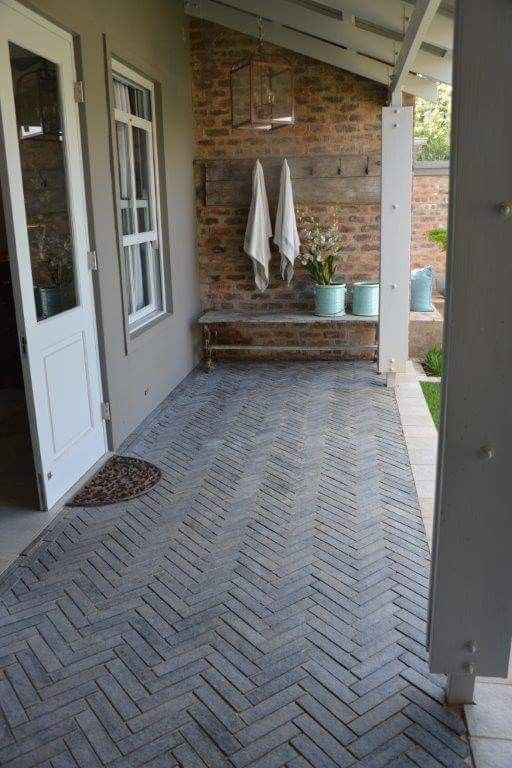 a brick patio with potted plants and towels hanging on the wall next to it