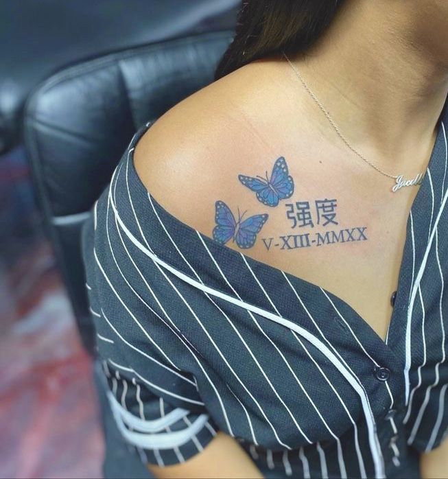 a woman with a blue butterfly tattoo on her upper arm and chest, in front of a black chair