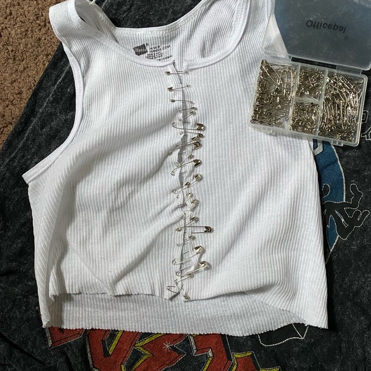 a white shirt with laces on it sitting next to other clothing and accessories laying on the floor