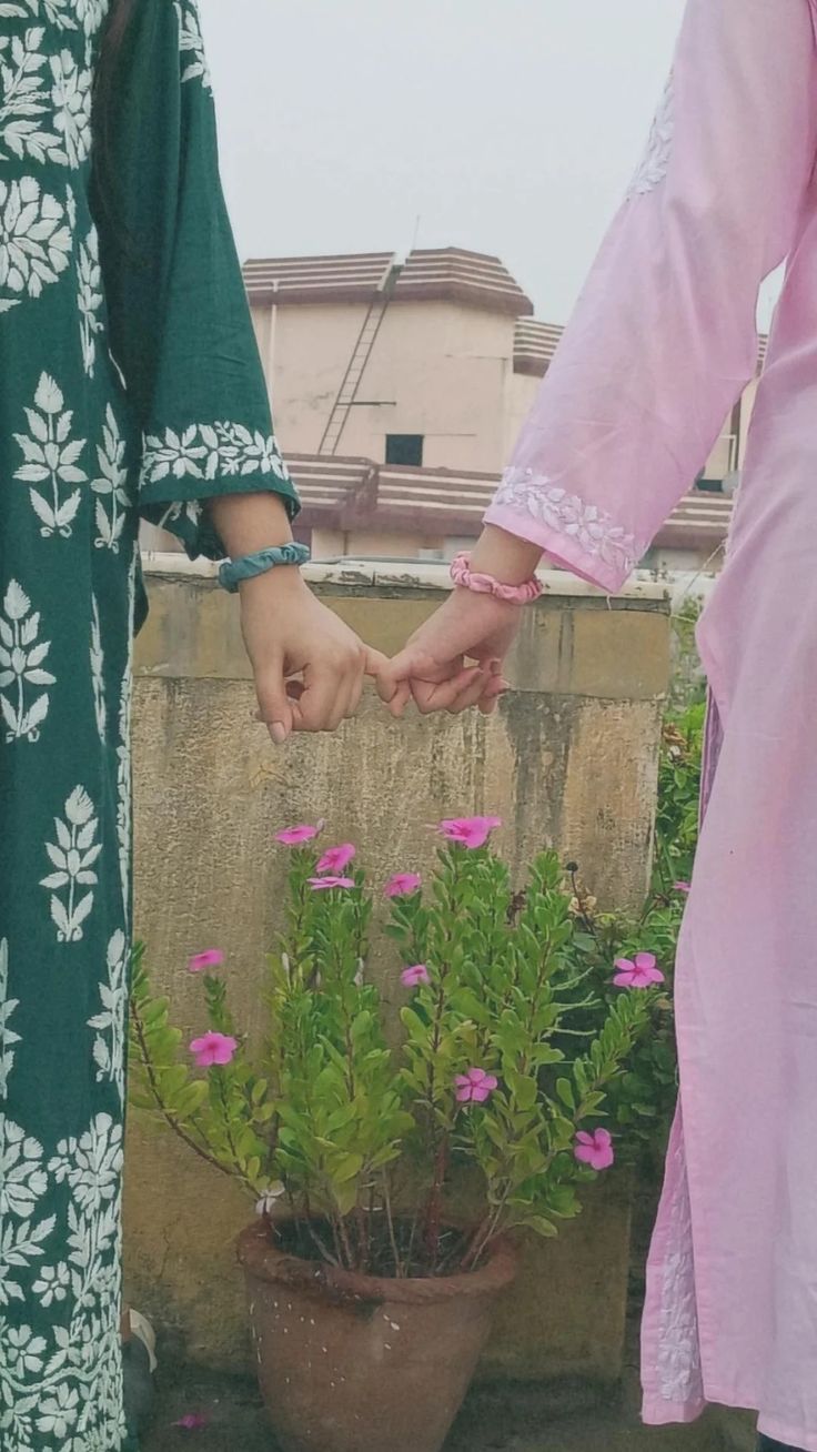 two people holding hands over a potted plant