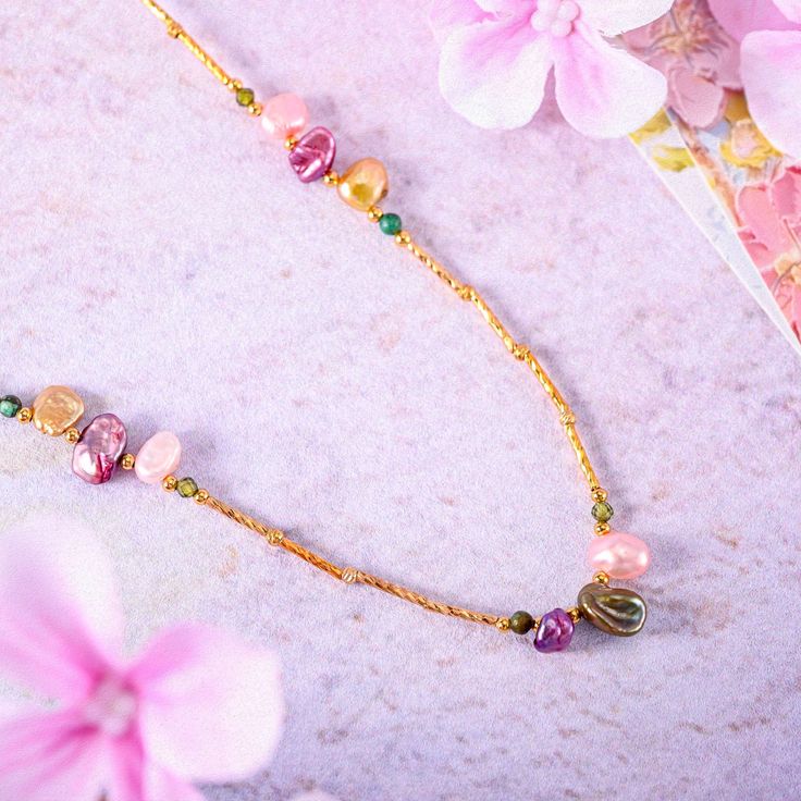 Infuse your style with the free-spirited elegance of our Boho Baroque Pearl Chain Necklace, a piece that effortlessly combines modern bohemian charm with timeless sophistication. This necklace features a unique arrangement of baroque pearls, each with its own distinctive shape and iridescent hue, set along an 18K gold-plated brass chain. The pearls, in shades of pink, gold, and deep purple, are interspersed with delicate green enamel beads, creating a vibrant and harmonious design. The asymmetri Elegant Festival Necklaces With Delicate Chain, Elegant Festival Necklace With Delicate Chain, Elegant Multicolor Necklace With Delicate Chain, Elegant Pink Necklaces For Festivals, Pink Bohemian Necklace With Adjustable Chain, Bohemian Long Necklace With Delicate Chain, Bohemian Gold Beaded Necklaces With Delicate Chain, Gold Bohemian Beaded Necklace With Delicate Chain, Bohemian Gold Beaded Necklace With Delicate Chain