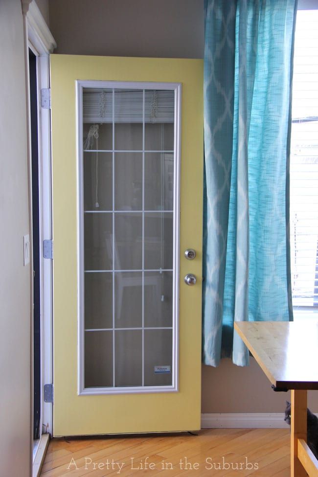 an empty room with a yellow door and blue curtains