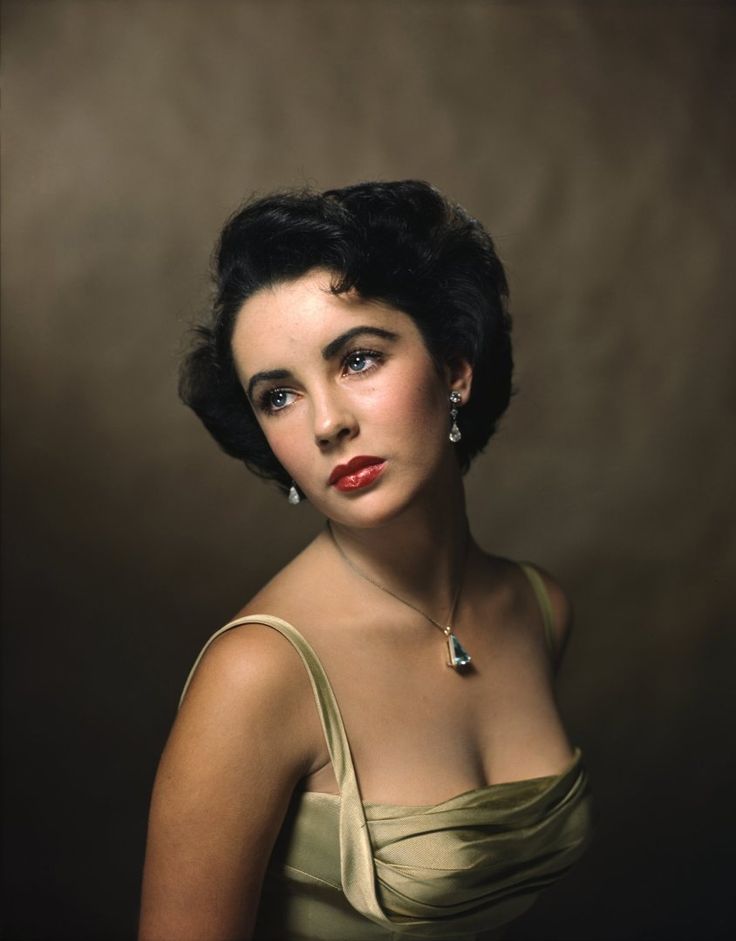 an old photo of a woman wearing a dress and diamond earring necklace, posing for a studio portrait