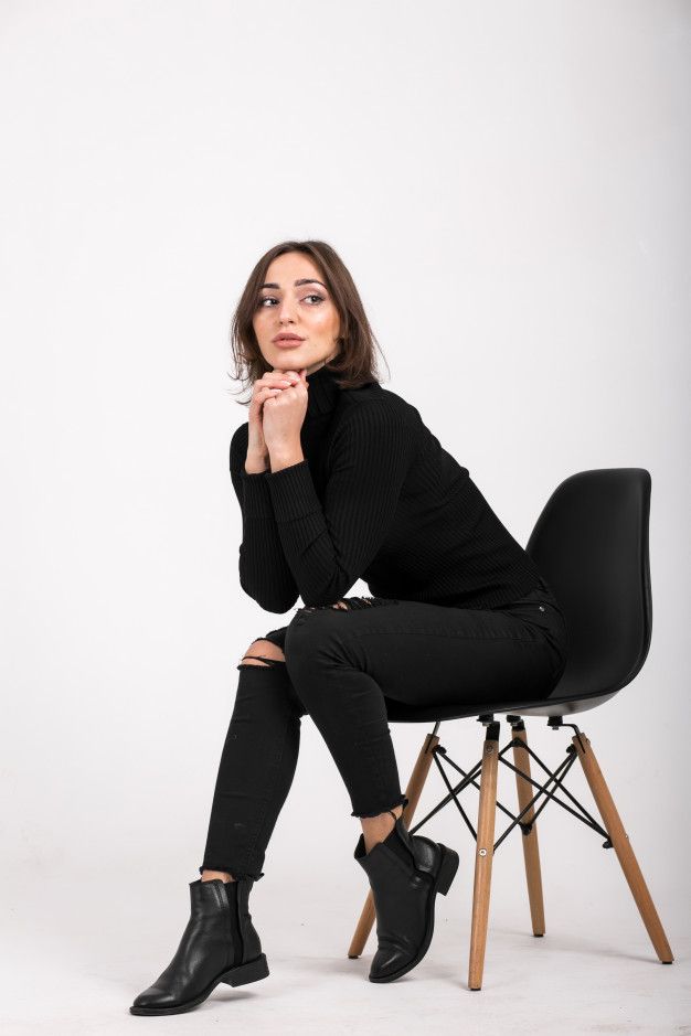 a woman sitting on top of a chair with her hand under her chin and looking at the camera