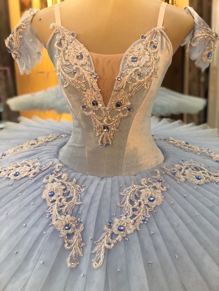 a ball gown is displayed on a mannequin in a store display case, with blue and white beading