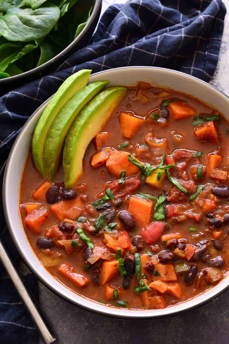 a white bowl filled with black bean and sweet potato soup next to a blue towel