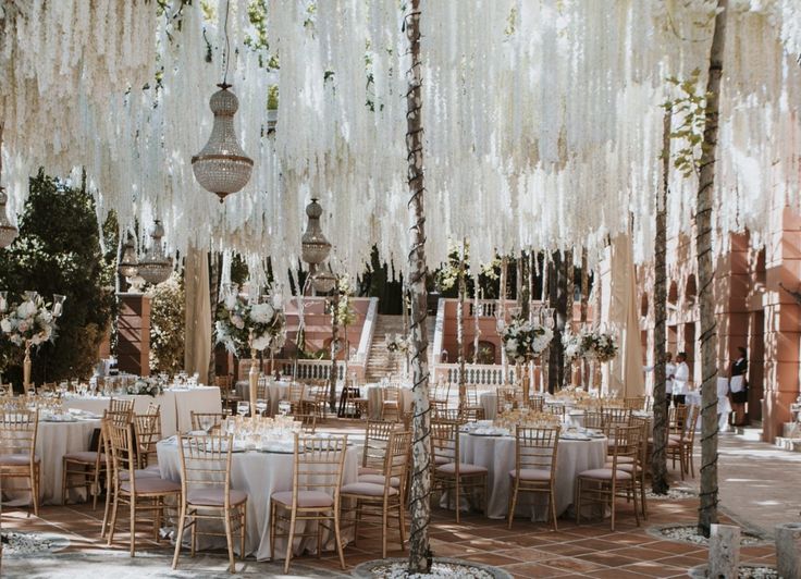 an outdoor dining area with tables, chairs and chandeliers hanging from the ceiling