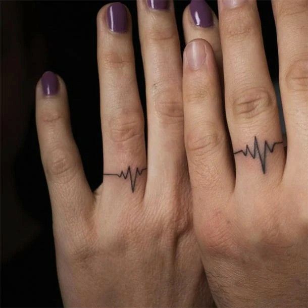 two fingers with heartbeat tattoos on them