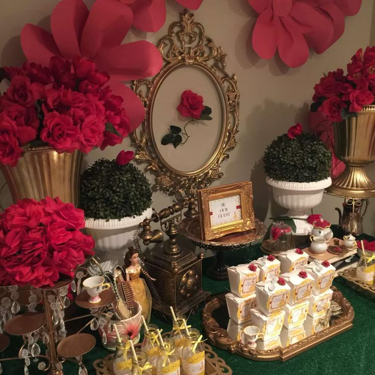 a table topped with lots of cakes and desserts covered in red flowers next to a mirror